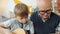 Caring grandfather helping cute kid teaching guitar playing at home together