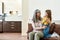 Caring grandmother talking to her adorable sweet granddaughter, looking at her with tender and love while sitting