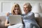 Caring grown up daughter teaching elderly mother to use laptop