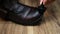 Caring for leather men`s shoes, apply brown cream on old worn out shoes, close-up, a shoemaker wipes shoes