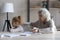 Caring mature grandmother helping to unhappy little granddaughter with homework