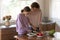 Caring mom and teen daughter cooking in kitchen together