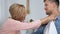 Caring mother attaching napkin to neck of son before tea drinking overprotection