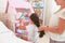 Caring mother braids her daughter`s hair when the girl is playing with toys