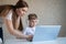 A caring mother helps her child do homework on a laptop. A woman and her little son are looking at a computer monitor.