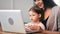 Caring mother hugging and stroking cute daughter sitting in front of laptop. 4k Dragon RED camera