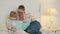 Caring mother reading book to adorable little girl sitting in bed in bedroom together