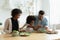 Caring multiethnic couple teach small daughter cook vegetable salad