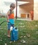 Caring for nature. Shot of a young boy filling a watering can with a hosepipe.