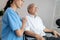 Caring nurse and a contented senior man in a wheel chair at home.