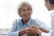 Caring nurse holding older woman hands, expressing support and empathy