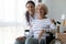 Caring nurse hug elderly disabled woman in wheelchair posing indoors