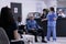 Caring nurse taking senior patient to see medic for clinical consult while african american doctor is completing form