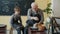 Caring senior grandfather showing grandson how to work with clay on throwing-wheel in workshop