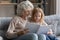 Caring senior grandmother reading book with little granddaughter