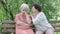 Caring senior woman calming down friend sitting on bench in summer park. Portrait of Caucasian retirees talking outdoors