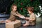 Caring sister giving present to her toddler brother under a christmas tree