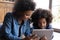 Caring smiling young African American mother using tablet with kid.