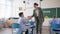 Caring teacher brings glass of water to a boy at school, pupils sit at their desks during a lesson or break in classroom