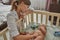 Caring woman comforting teething baby in crib