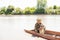 Caring young man in camo posing at camera, while hugging cute spotted setter, while sitting in boat.