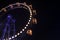 Carnival entertainment Ferris wheel motion with dark blue illumination from frame and yellow from cabins at night time black sky