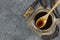 Carob molasses in glass bowl and in wooden spoon and carob pods on rustic background