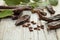 Carob pods with seeds and green leaves on white wooden table