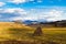 Carpathian Mountains in Transcarpathia, golden light of late evening sun in valley, white clouds make shadows on farm field