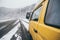 Carpathians, Ukraine - December 2019: yellow camper van driving on the snowy dirt road with winter forest on background