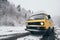 Carpathians, Ukraine - December 2019: yellow camper van driving on the snowy dirt road with winter forest on background