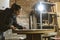 Carpenter / Artisan girl is concentrated working on an old wood table in her workshop. Woman restores an antique furniture