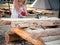 Carpenter bare-chested in medieval cotton clothes working with hardwood with an ax. A man manually cuts a wooden board