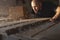 A carpenter blows sawdust off a board