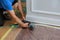 Carpenter brad using nail gun to Moulding trim, with the warning label that power tools