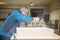 Carpenter cleans the wood with a brush raising dust in his workshop