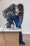 A carpenter with a corded jigsaw cutting a part of the wooden surface (board