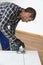 A carpenter with a corded jigsaw cutting a part of the wooden surface board