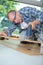 Carpenter cutting laminated planks for layered parquet using bandsaw