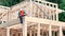 Carpenter hammering nail while constructing wooden frame two-story house.