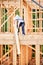 Carpenter holding large beam while builds wooden frame house near the forest.