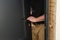 A carpenter installs a metal doorknob for an interior door,