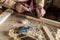 Carpenter man scraping curled wood scraps with hand plane tool and wooden plank