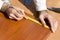 Carpenter measures the distance using a measure and marks with a carpenter`s pencil.