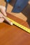 The carpenter measures the distance using a measure and marks with a carpenter`s pencil.