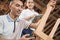 Carpenter measures the wood against the background of a furniture business woman using a tablet