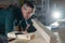 Carpenter measures a wooden board while working in a workshop.