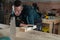 Carpenter measures a wooden board while working in a workshop.