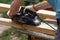 A carpenter planks wood with an electric plane. Woodworking carpentry. Close-up. Man in the garden sanding wooden planks