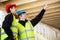 Carpenter Pointing Towards Roof While Standing By Colleague